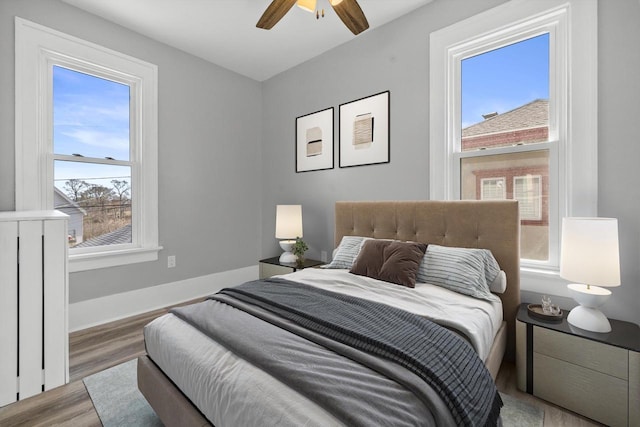 bedroom with a ceiling fan, wood finished floors, and baseboards