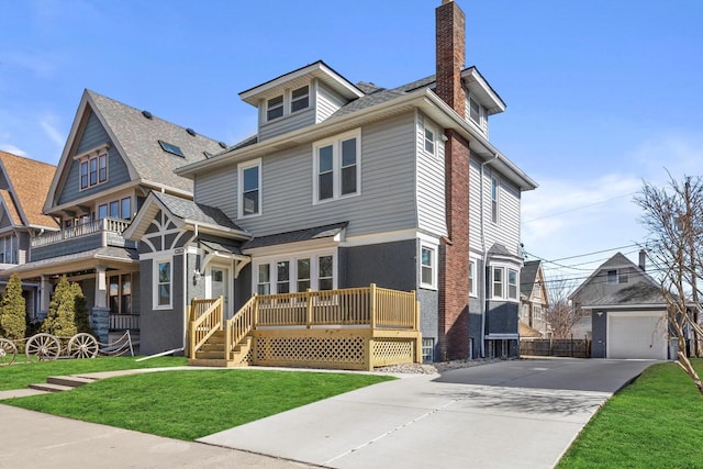 traditional style home with a front lawn, roof with shingles, a chimney, a deck, and a garage