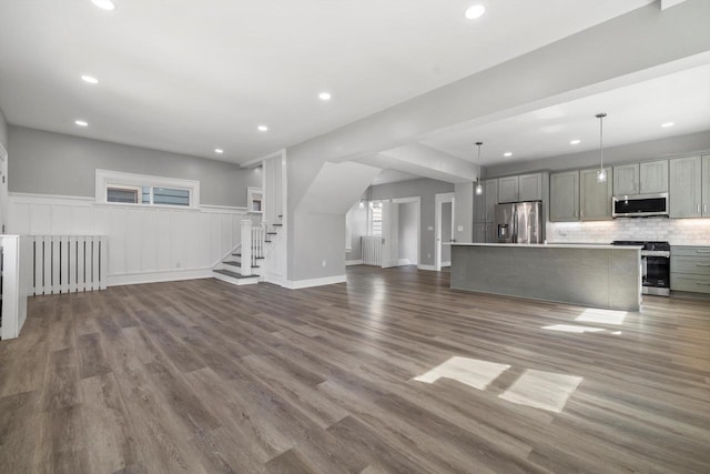 unfurnished living room with wainscoting, recessed lighting, stairs, and wood finished floors