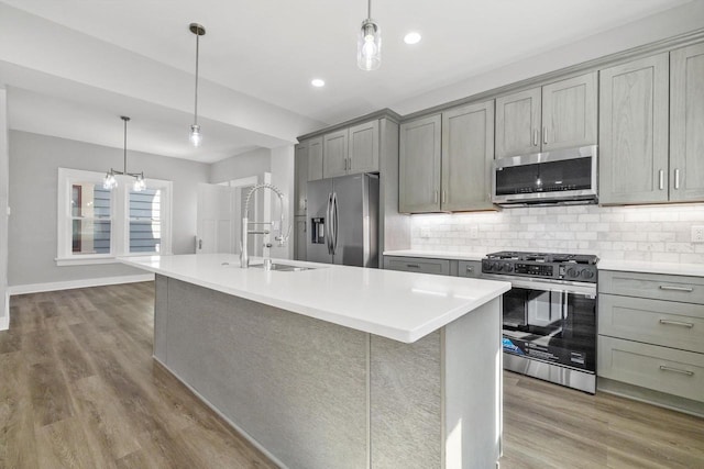 kitchen with tasteful backsplash, gray cabinets, appliances with stainless steel finishes, and a sink