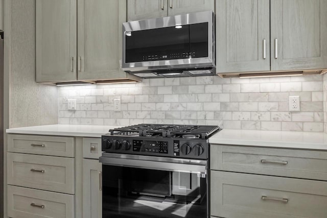 kitchen featuring tasteful backsplash, stainless steel microwave, light countertops, and range with gas stovetop