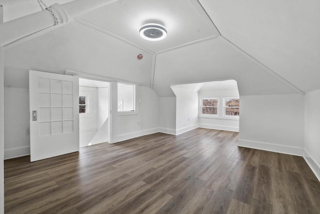 additional living space with dark wood finished floors, baseboards, and lofted ceiling