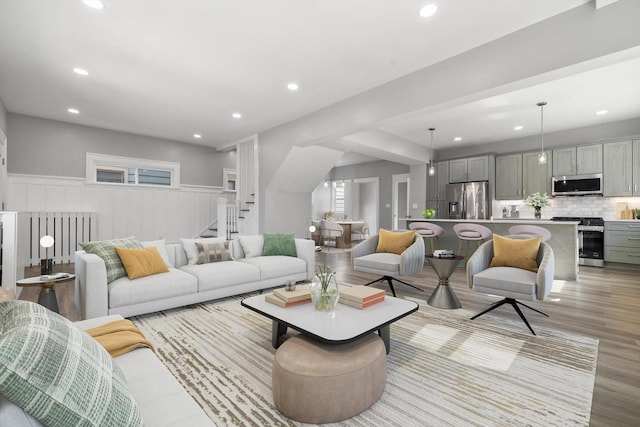 living area with recessed lighting, a wainscoted wall, and stairs