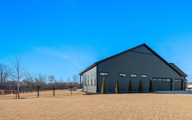 view of property exterior featuring a lawn, driveway, an attached garage, and fence