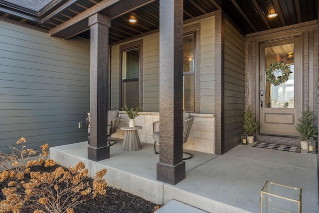 view of exterior entry with stone siding and a porch