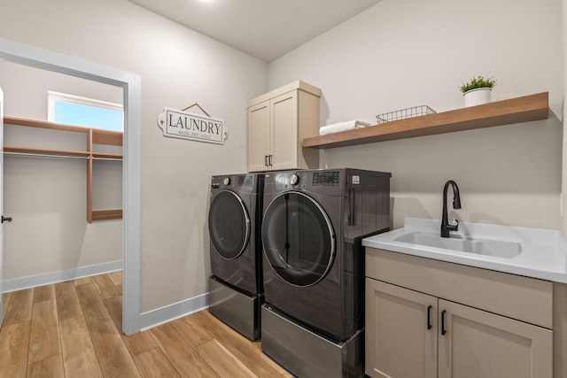 laundry room with light wood-type flooring, independent washer and dryer, a sink, cabinet space, and baseboards