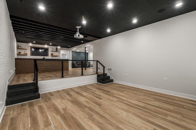 interior space featuring visible vents, wood finished floors, brick wall, a dry bar, and stairs