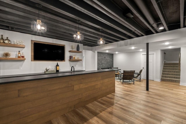 bar featuring decorative light fixtures, stairway, beamed ceiling, light wood-style flooring, and wet bar