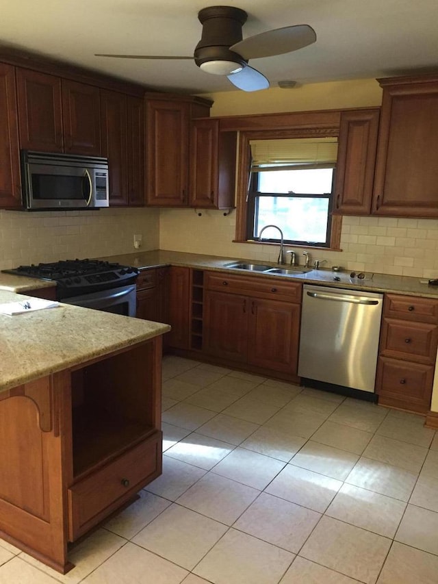 kitchen featuring a ceiling fan, a sink, backsplash, stainless steel appliances, and light tile patterned floors