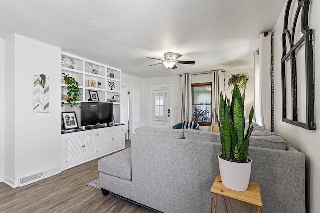 living area with a ceiling fan, wood finished floors, and visible vents