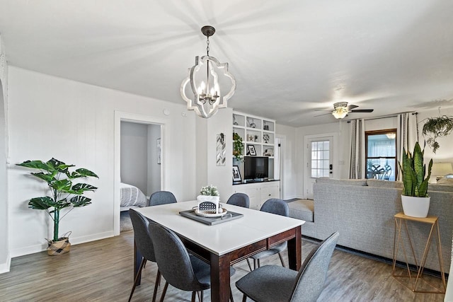 dining area with ceiling fan with notable chandelier, baseboards, and wood finished floors