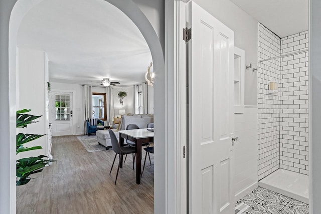 hallway with arched walkways and wood finished floors