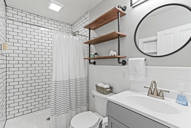 full bathroom with toilet, vanity, and a tile shower