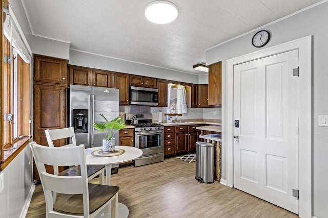 kitchen featuring light countertops, light wood-style flooring, crown molding, and stainless steel appliances