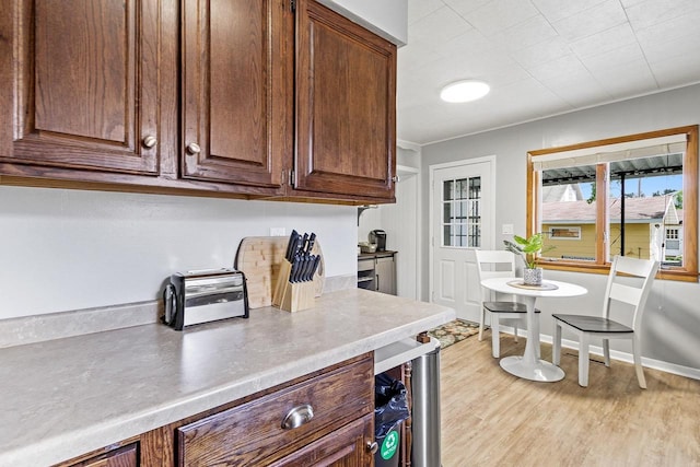 kitchen with light wood finished floors, beverage cooler, light countertops, and baseboards