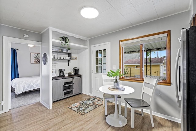 dining area with light wood-style flooring, baseboards, and ornamental molding