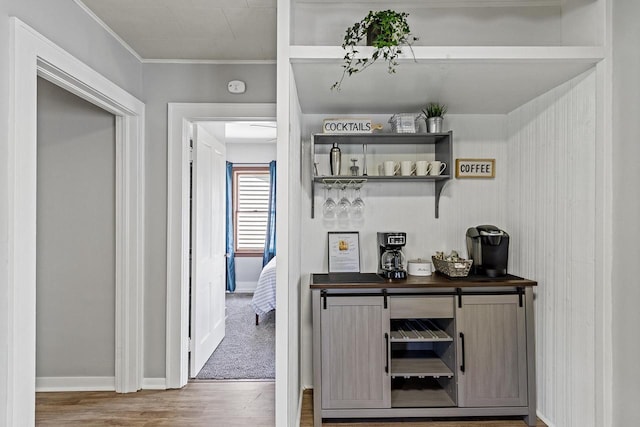 bar featuring wood finished floors, baseboards, and ornamental molding