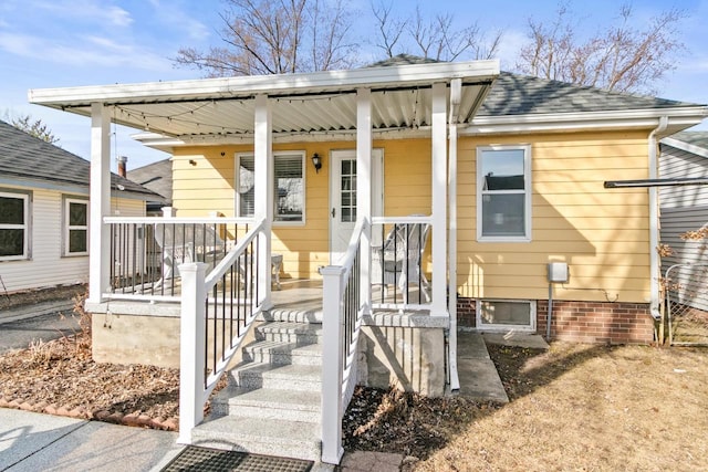 exterior space featuring covered porch and a shingled roof