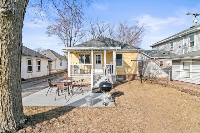 rear view of property featuring a patio area and a shingled roof