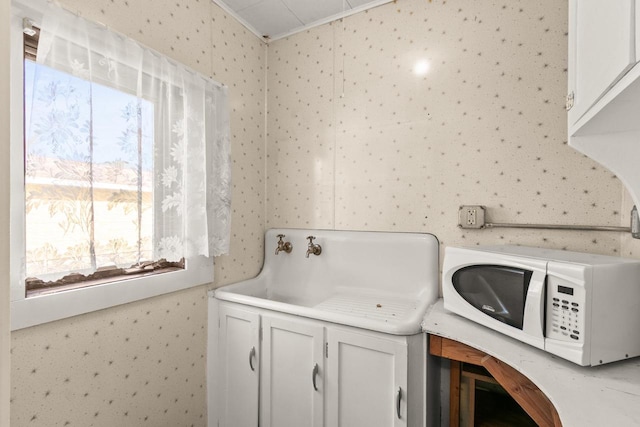 laundry area with a sink, crown molding, and wallpapered walls