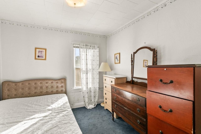 bedroom featuring dark carpet and baseboards