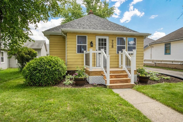 bungalow-style home featuring a shingled roof and a front yard