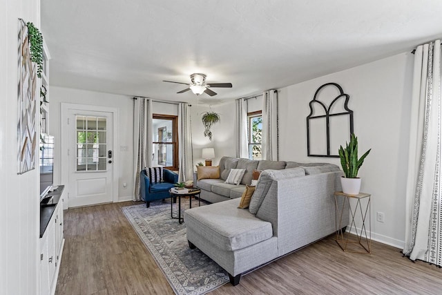 living area featuring baseboards, wood finished floors, and a ceiling fan