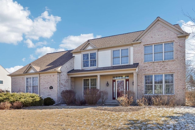 traditional-style home featuring brick siding and a shingled roof