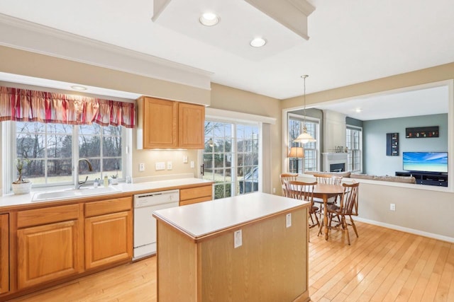 kitchen with open floor plan, light countertops, light wood-style flooring, white dishwasher, and a sink