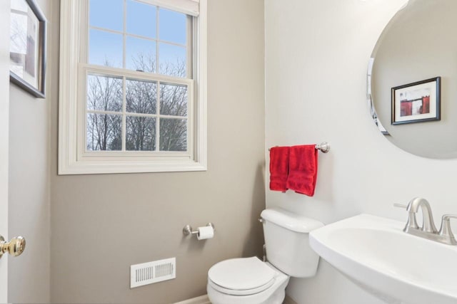 half bathroom featuring a sink, visible vents, and toilet