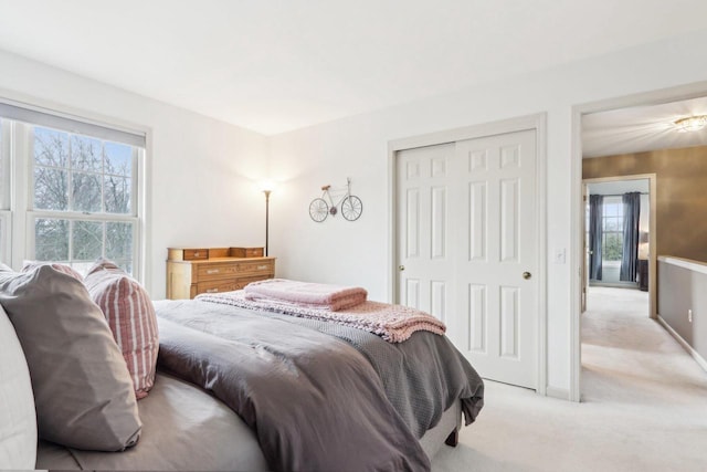 bedroom with light carpet, baseboards, and a closet