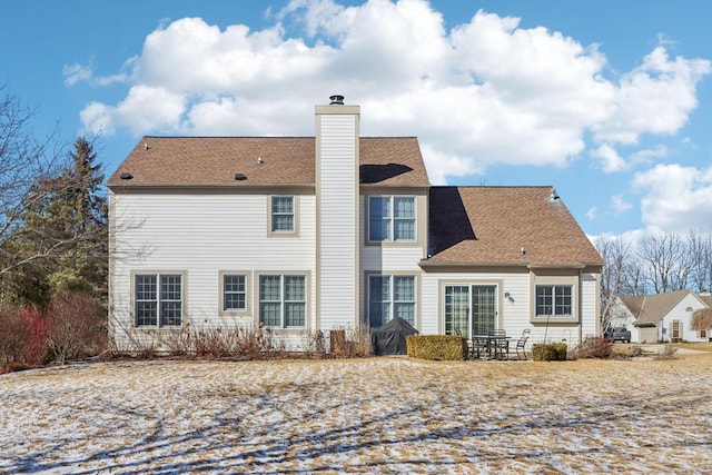 rear view of house featuring a shingled roof and a chimney