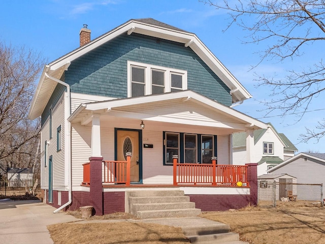 traditional style home with covered porch, a chimney, and fence