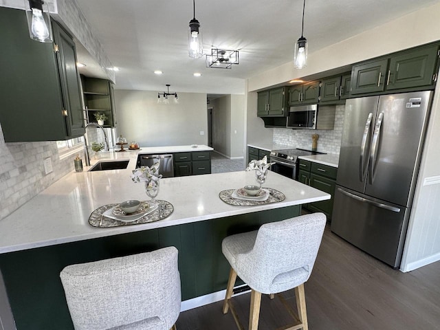 kitchen with dark wood finished floors, a peninsula, a breakfast bar, appliances with stainless steel finishes, and backsplash