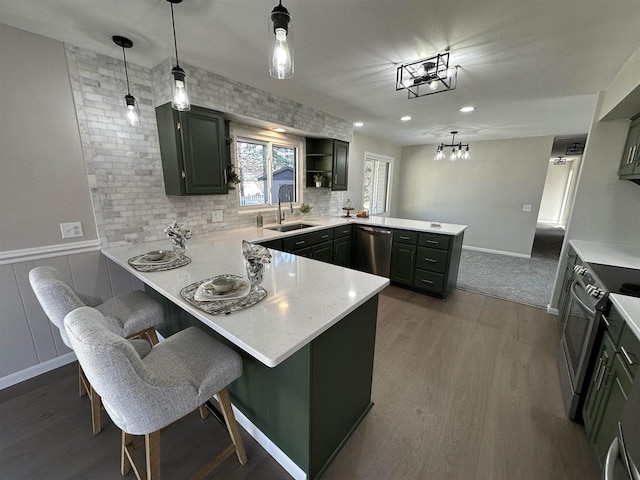 kitchen with decorative backsplash, a peninsula, dark wood-style floors, stainless steel appliances, and a sink