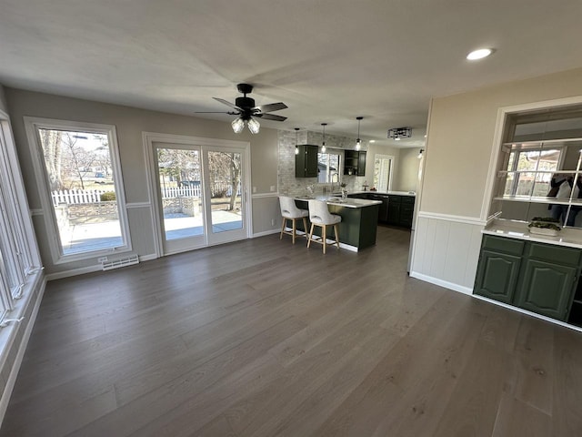 interior space featuring visible vents, a breakfast bar, light countertops, a peninsula, and dark wood-style flooring