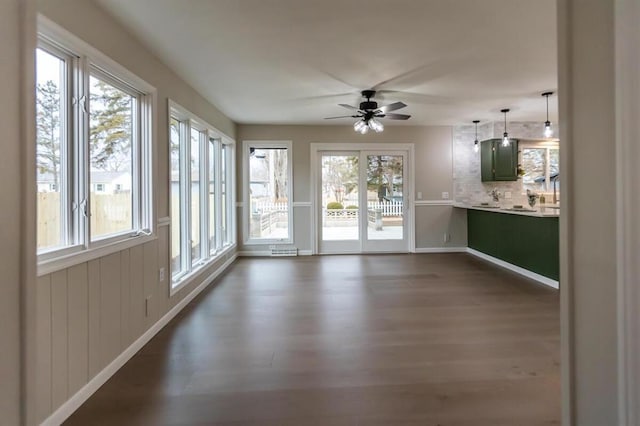 interior space featuring a ceiling fan, dark wood-type flooring, and baseboards