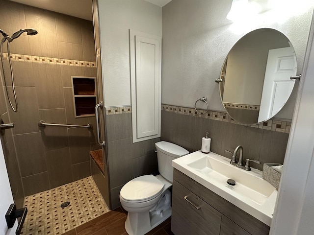 full bath featuring vanity, a stall shower, wainscoting, tile walls, and toilet