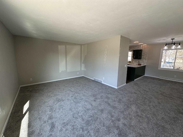 unfurnished living room featuring visible vents, dark carpet, a baseboard heating unit, and baseboards