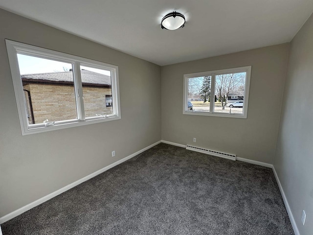 unfurnished room with a baseboard heating unit, baseboards, and dark carpet