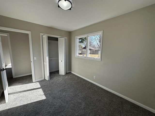 unfurnished bedroom with a closet, baseboards, and dark colored carpet