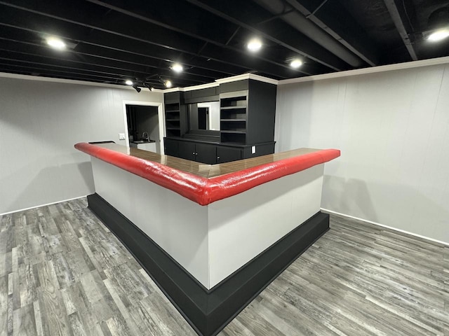 bar featuring baseboards, a bar, and wood finished floors