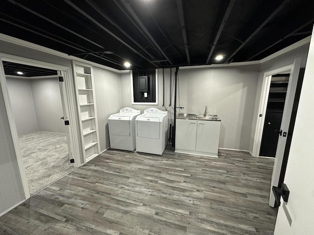 laundry area with wood finished floors, cabinet space, washing machine and dryer, and a sink