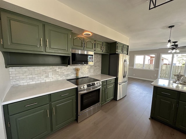 kitchen featuring green cabinetry, stainless steel appliances, and decorative backsplash