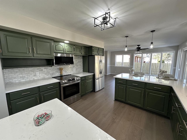 kitchen with dark wood-style floors, appliances with stainless steel finishes, green cabinets, and decorative backsplash