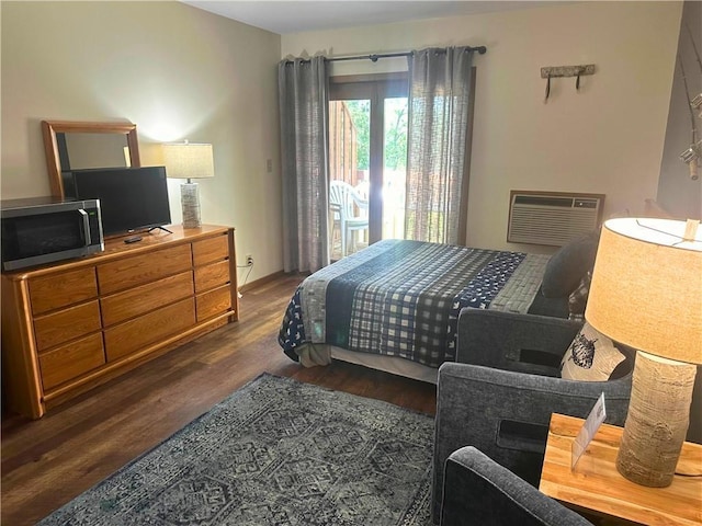 bedroom featuring access to exterior, an AC wall unit, and wood finished floors