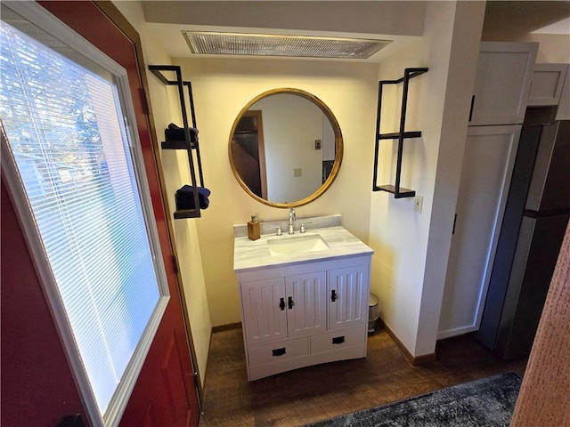 bathroom with visible vents, vanity, baseboards, and wood finished floors