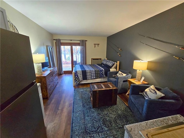 bedroom with freestanding refrigerator and wood finished floors