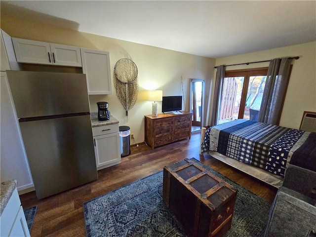 bedroom with dark wood-style floors, freestanding refrigerator, and access to exterior