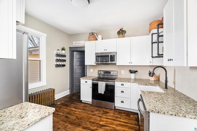 kitchen with dark wood finished floors, a sink, decorative backsplash, white cabinets, and appliances with stainless steel finishes